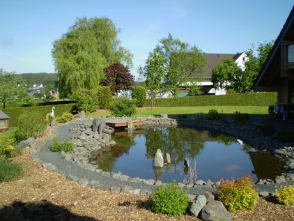 Teichanlage mit Wasserbausteinen und Bankirai-Terrasse über dem Teich